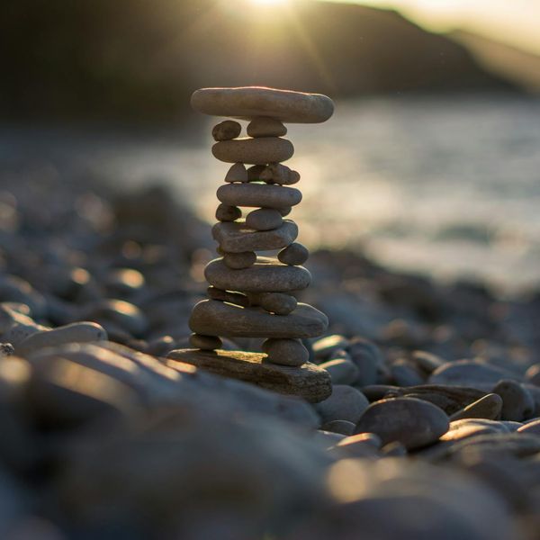 A balanced stack of stones on a serene beach at sunset.