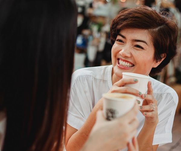 A group of friends laughing and talking together in a cafe.
